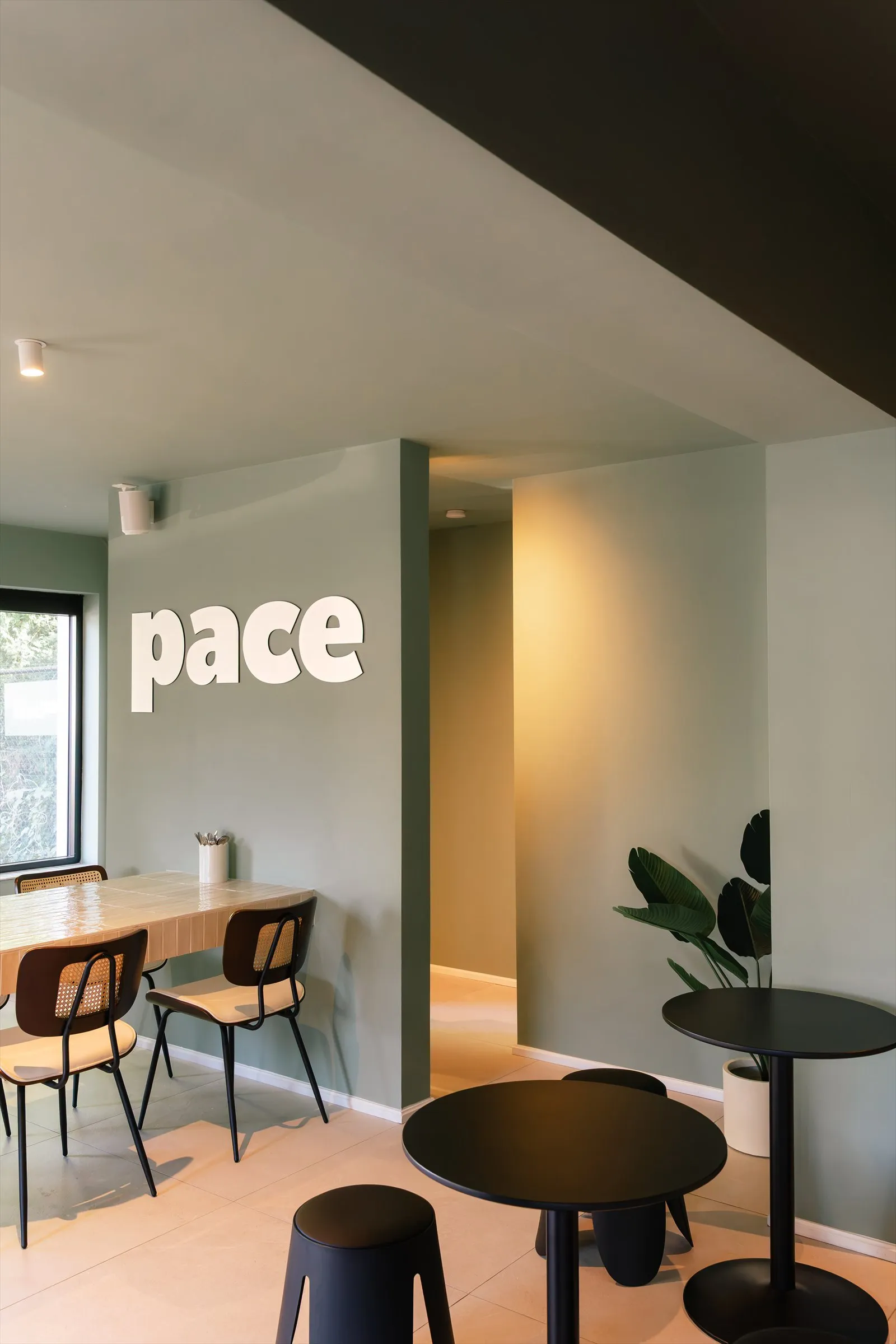 La salle de PACE Coffee Club : tables en bois, chaises et signature murale