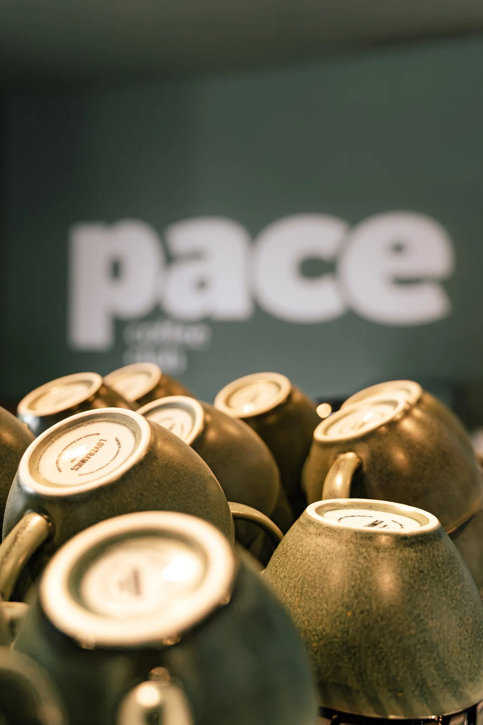 Tasses en grès empilées devant le mur pace coffee club